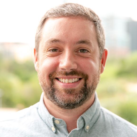 Adam Burgess, smiling, in a light blue shirt.